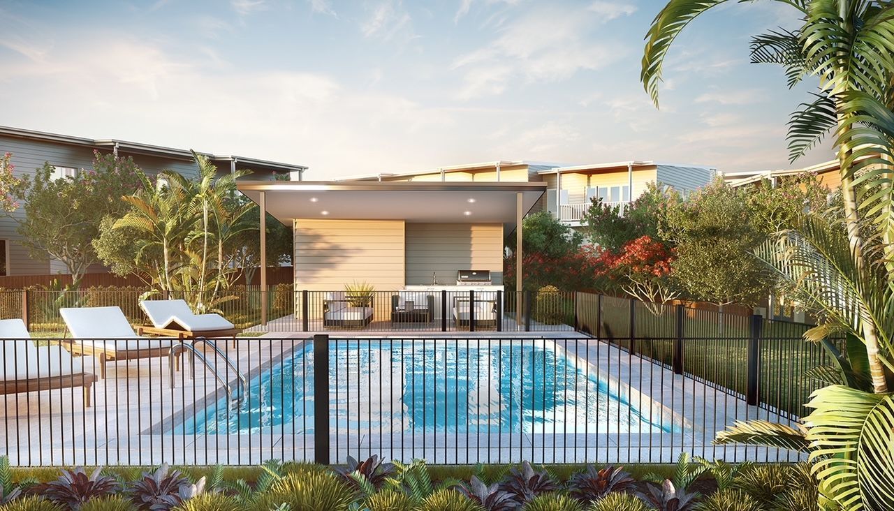 Modern resort pool with lounge chairs, palm trees, and a contemporary building at sunset