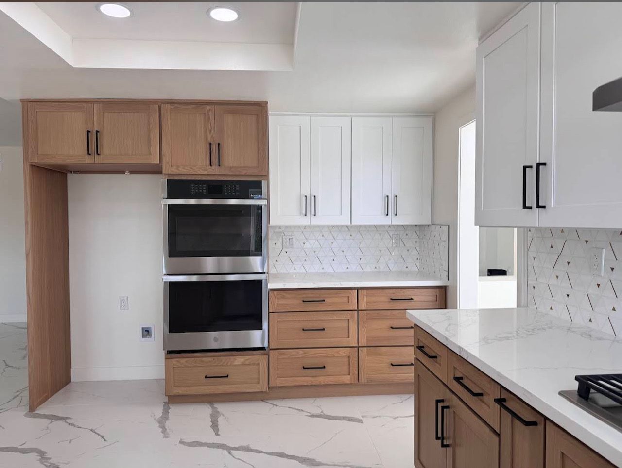 Bright kitchen with white cabinets, stainless steel appliances, butcher block island, and wood floors.