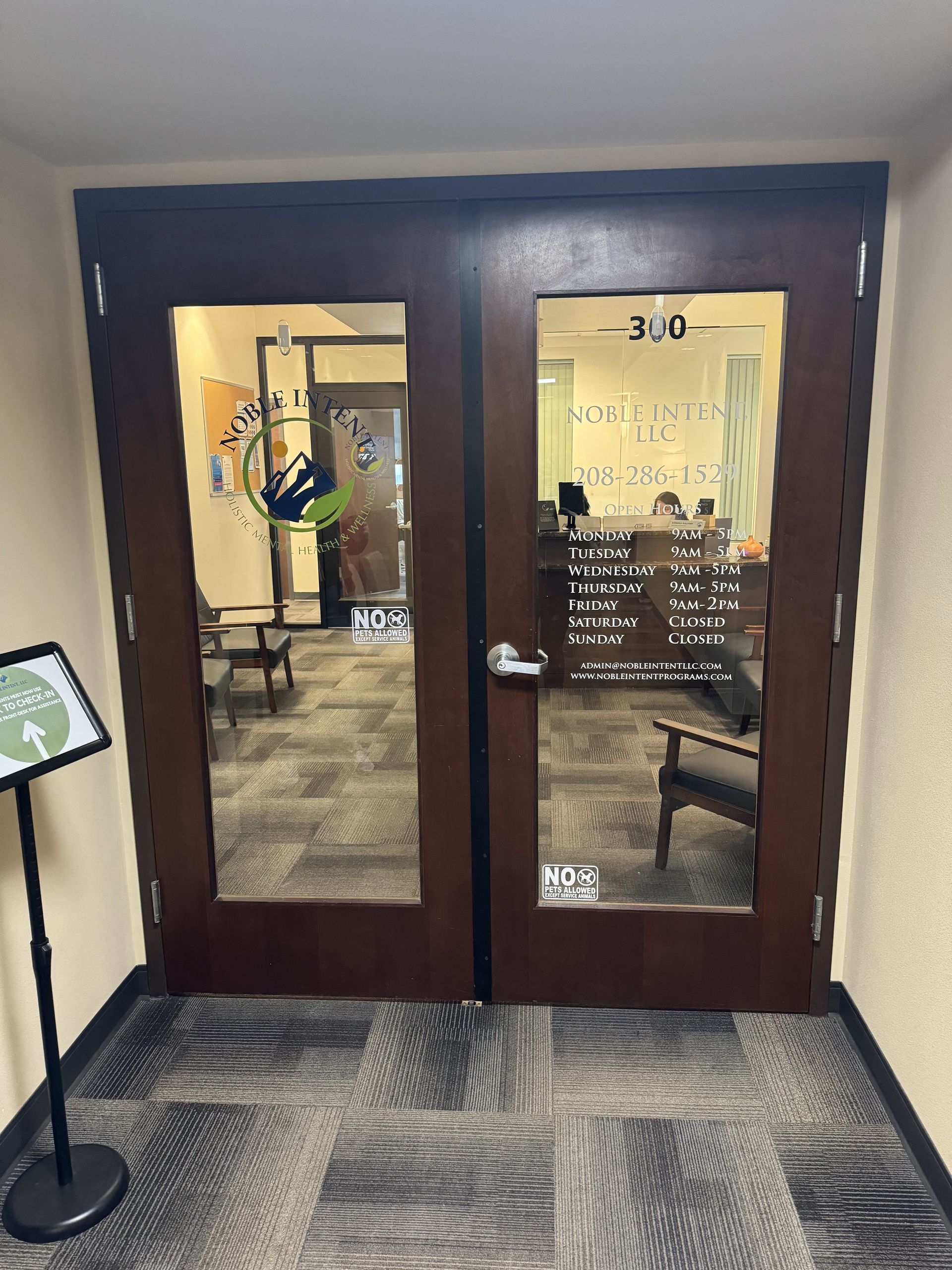 A hallway with a glass door and a sign in front of it.