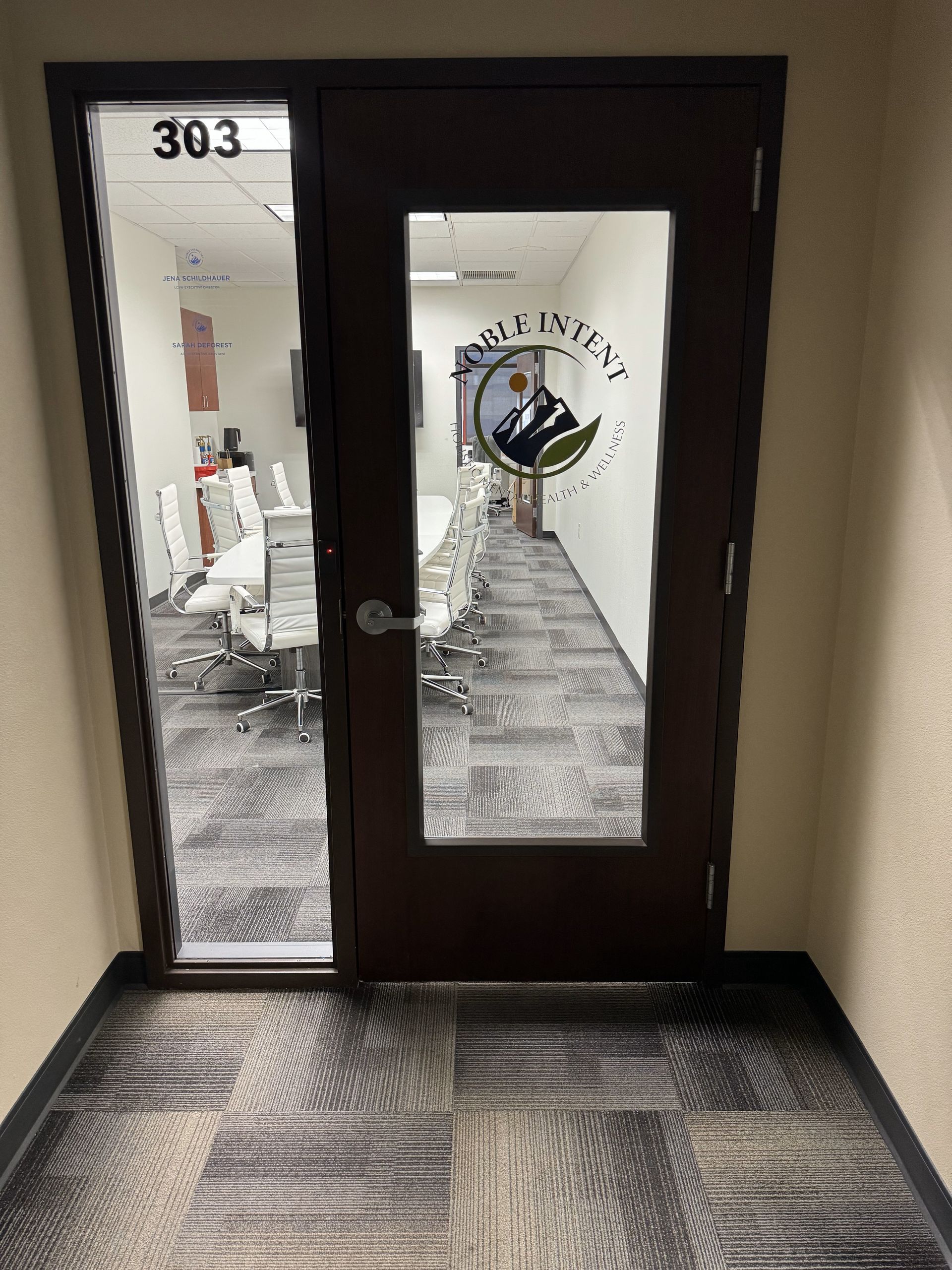 A hallway with a glass door leading to a conference room.