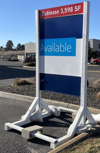 A blue and white sign that says `` available '' is sitting on the side of the road.