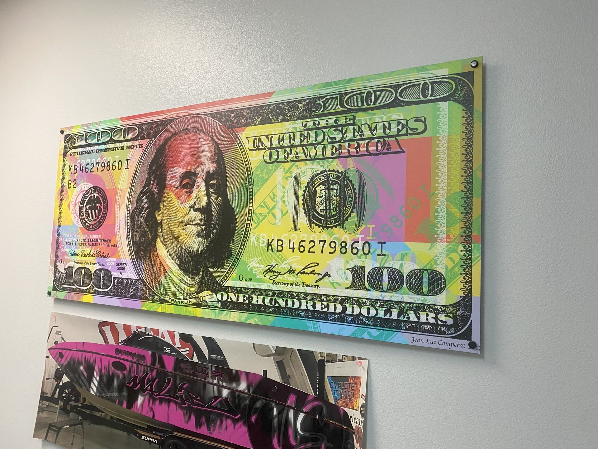 A painting of a 100 dollar bill is hanging on a wall.