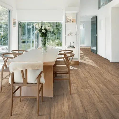 A dining room with a wooden table and chairs and a vase of flowers on the table.