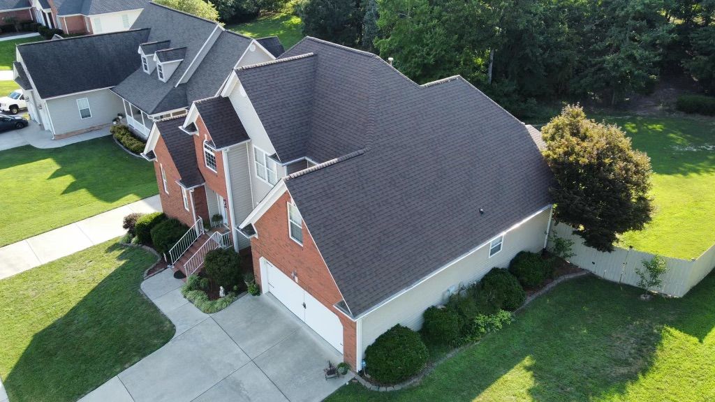 an aerial view of a large brick house with a black roof .