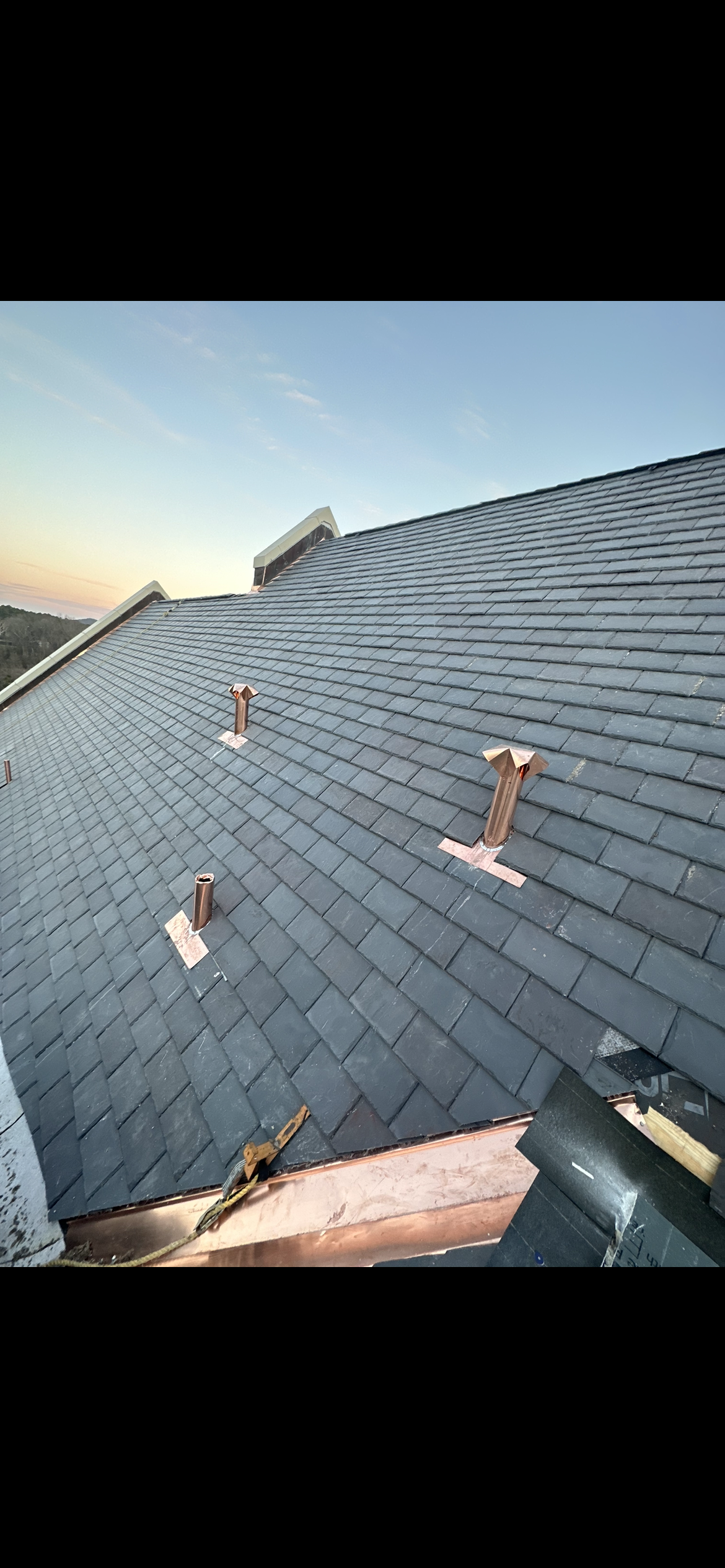 a roof with a lot of slate shingles and chimneys on it .