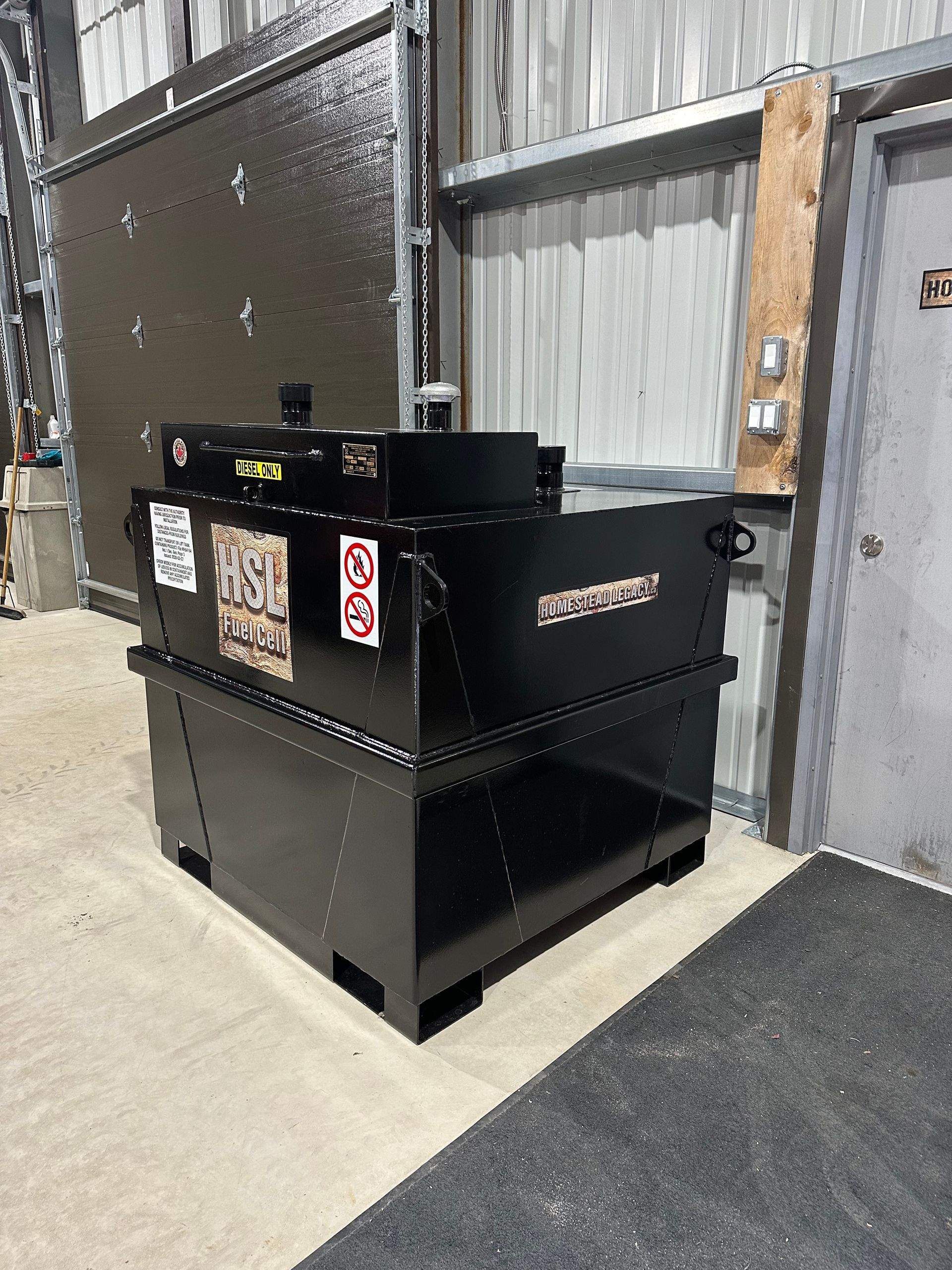A large black box is sitting in a warehouse next to a door.