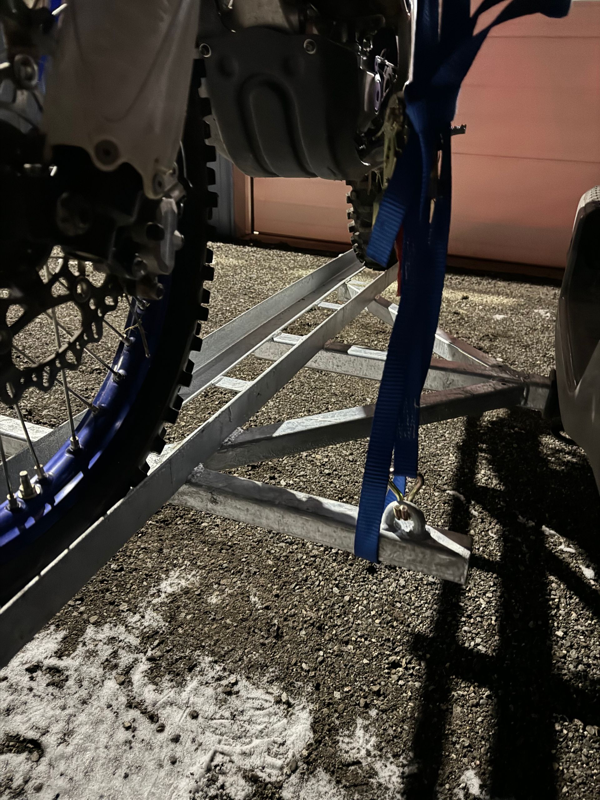 A dirt bike is sitting on a trailer attached to a car.