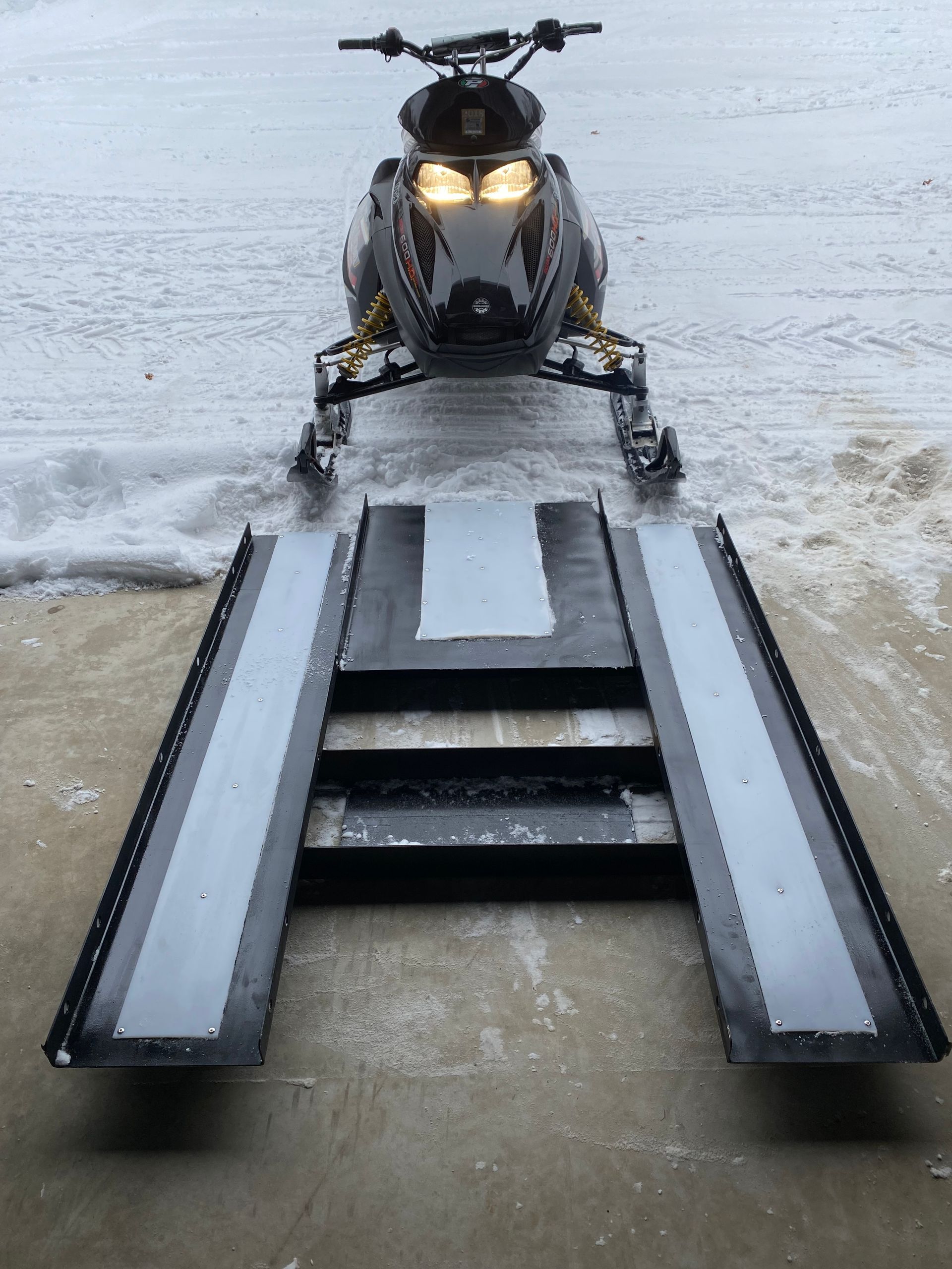 A snowmobile is parked on a ramp in the snow.