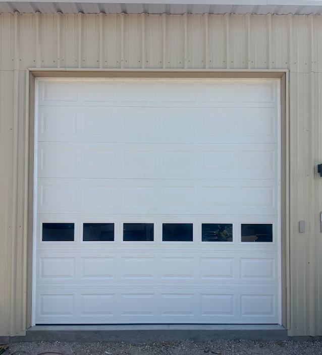 White garage door with a row of small windows on a beige building exterior.
