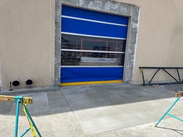 Industrial doorway with blue roll-up door, concrete wall, and barricade frame outside