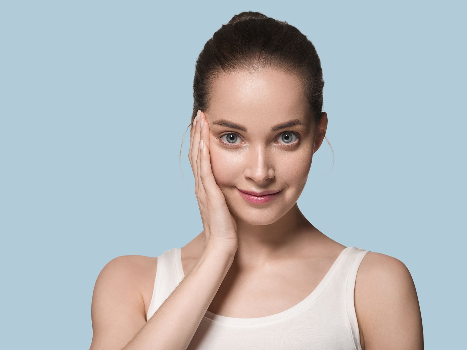 A woman is touching her face with her hand and smiling.