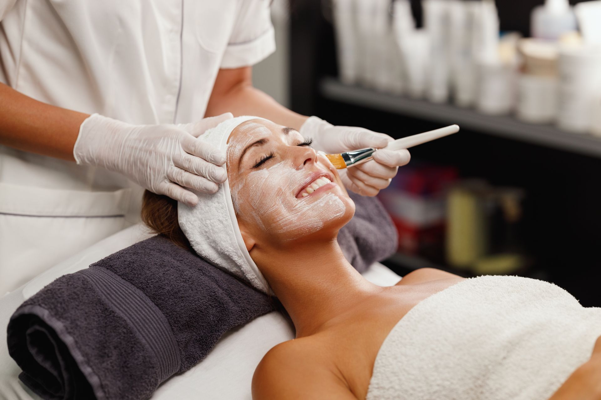 Facial treatment in a spa, with a masked client receiving product applied by a gloved esthetician
