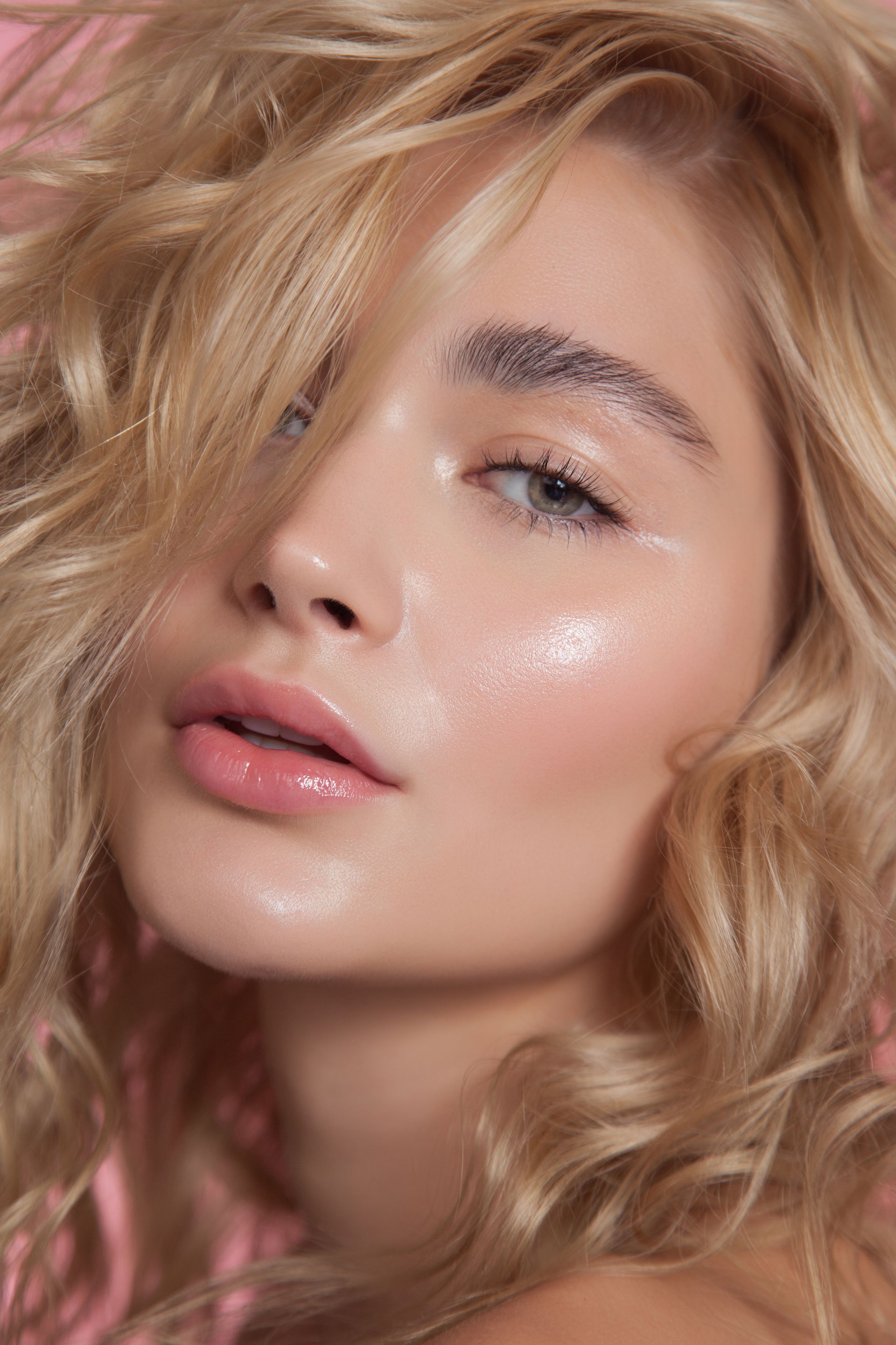 A close up of a woman 's face with her hair blowing in the wind.