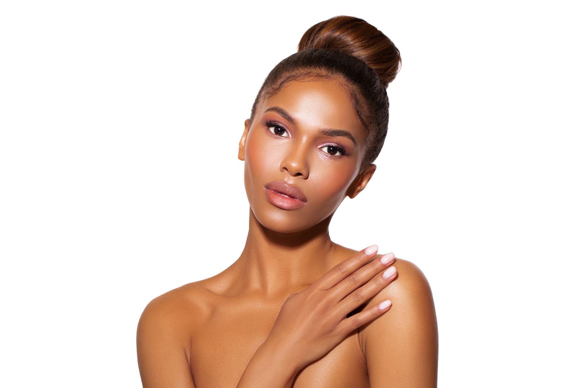 A woman with her hair in a bun is touching her shoulder.