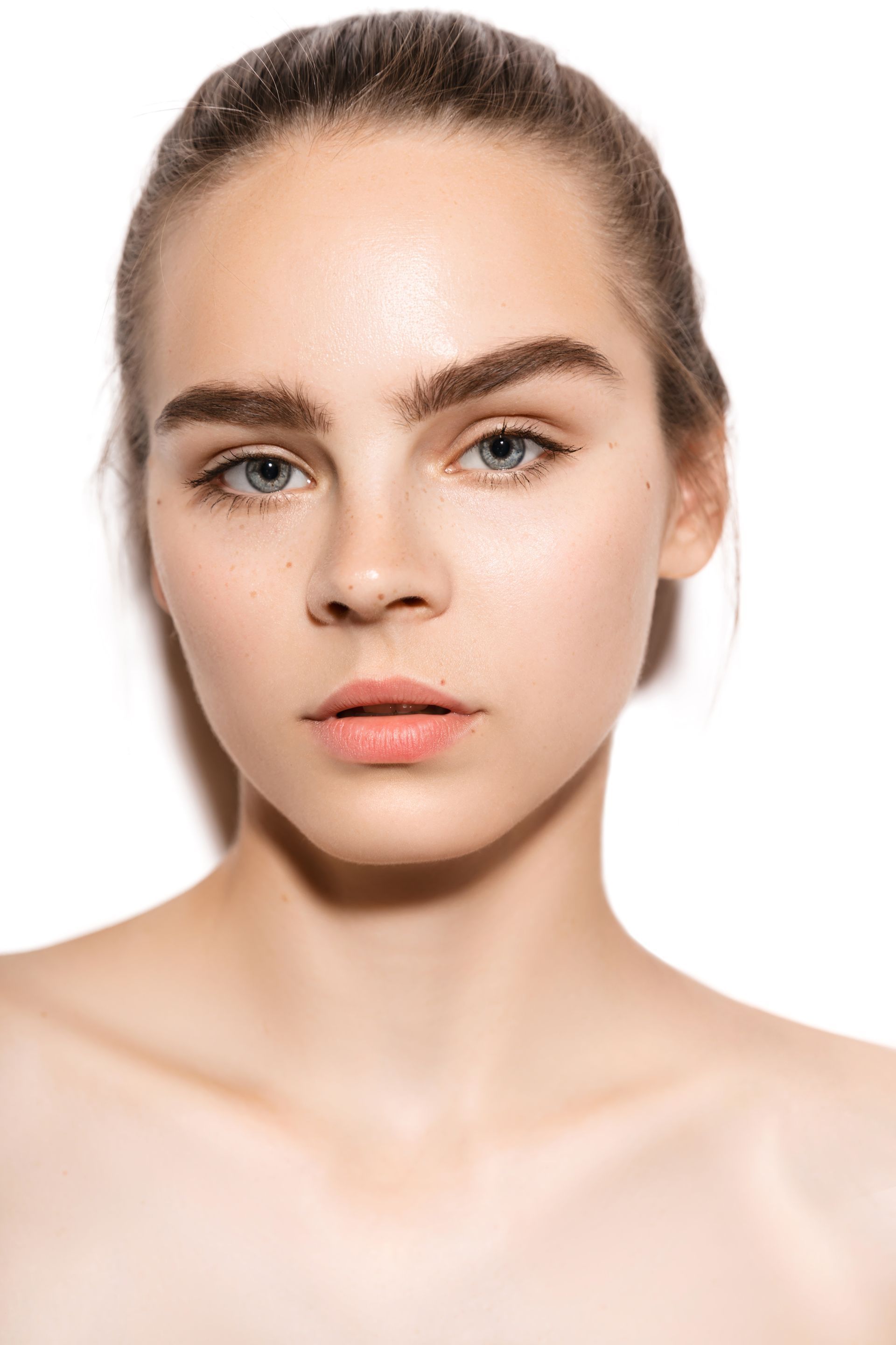 A close up of a woman 's face without makeup on a white background.