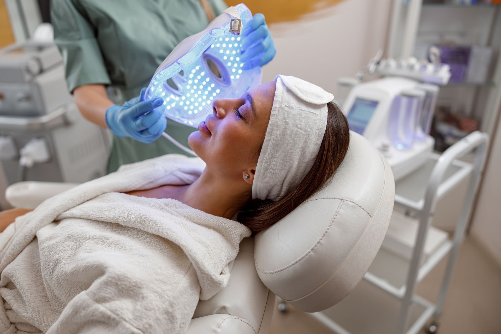 A woman is getting a led mask on her face in a beauty salon.