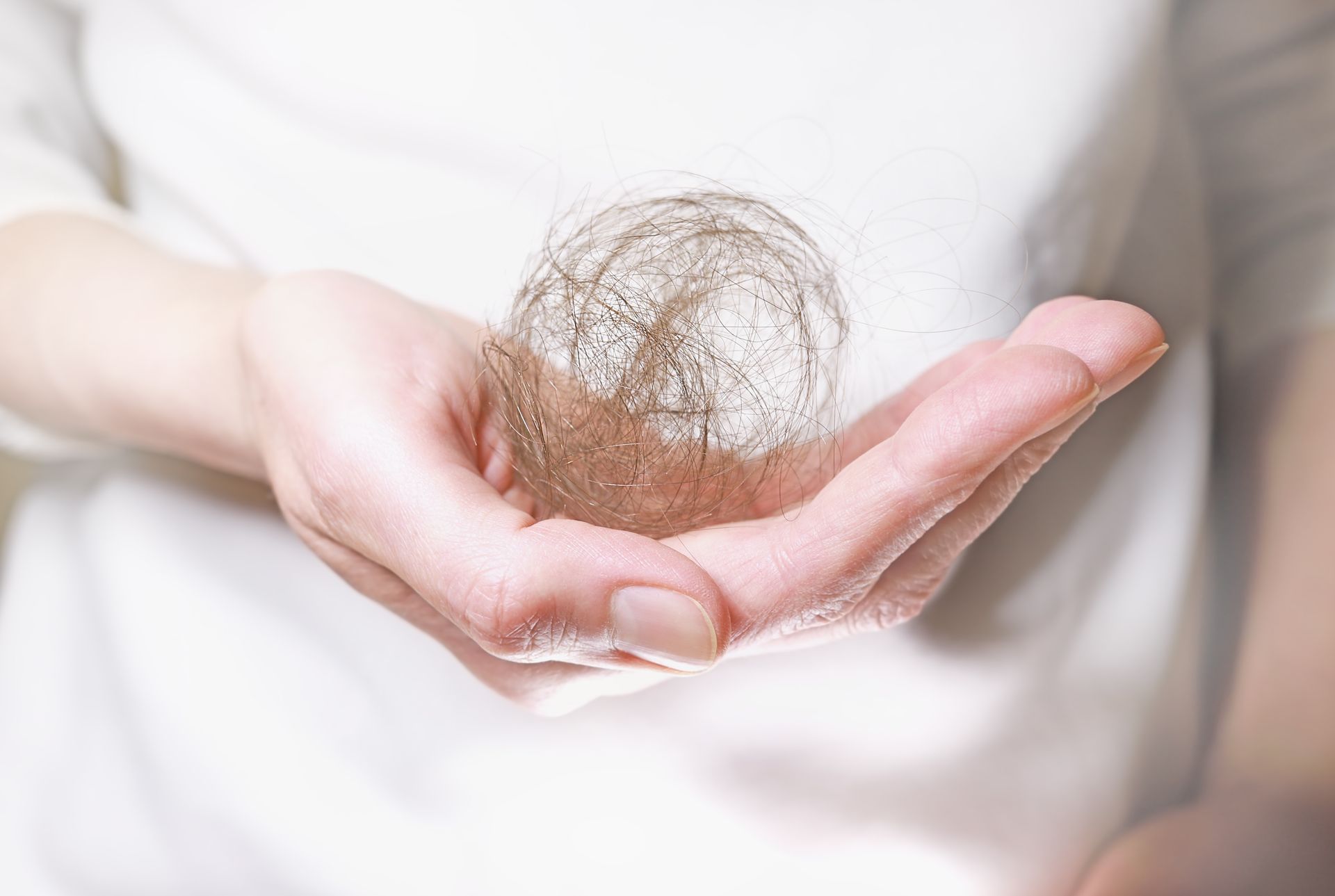 A woman is holding a ball of hair in her hand.