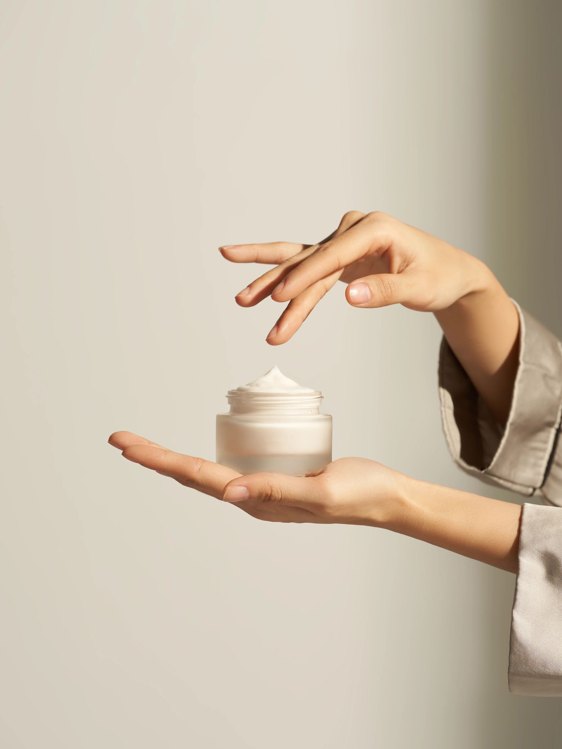 A woman is holding a jar of cream in her hand.