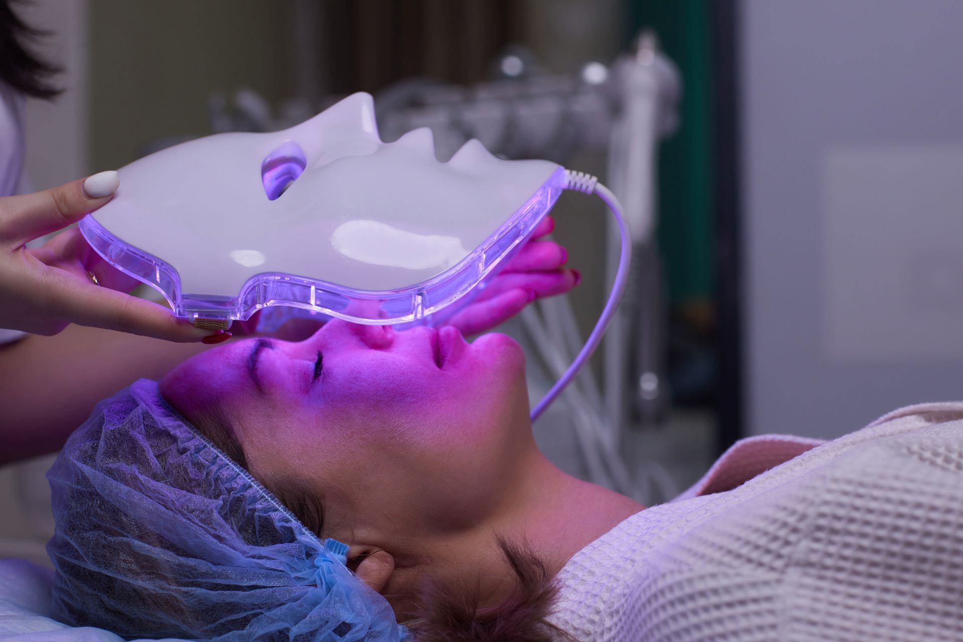 A woman is getting a led mask on her face.