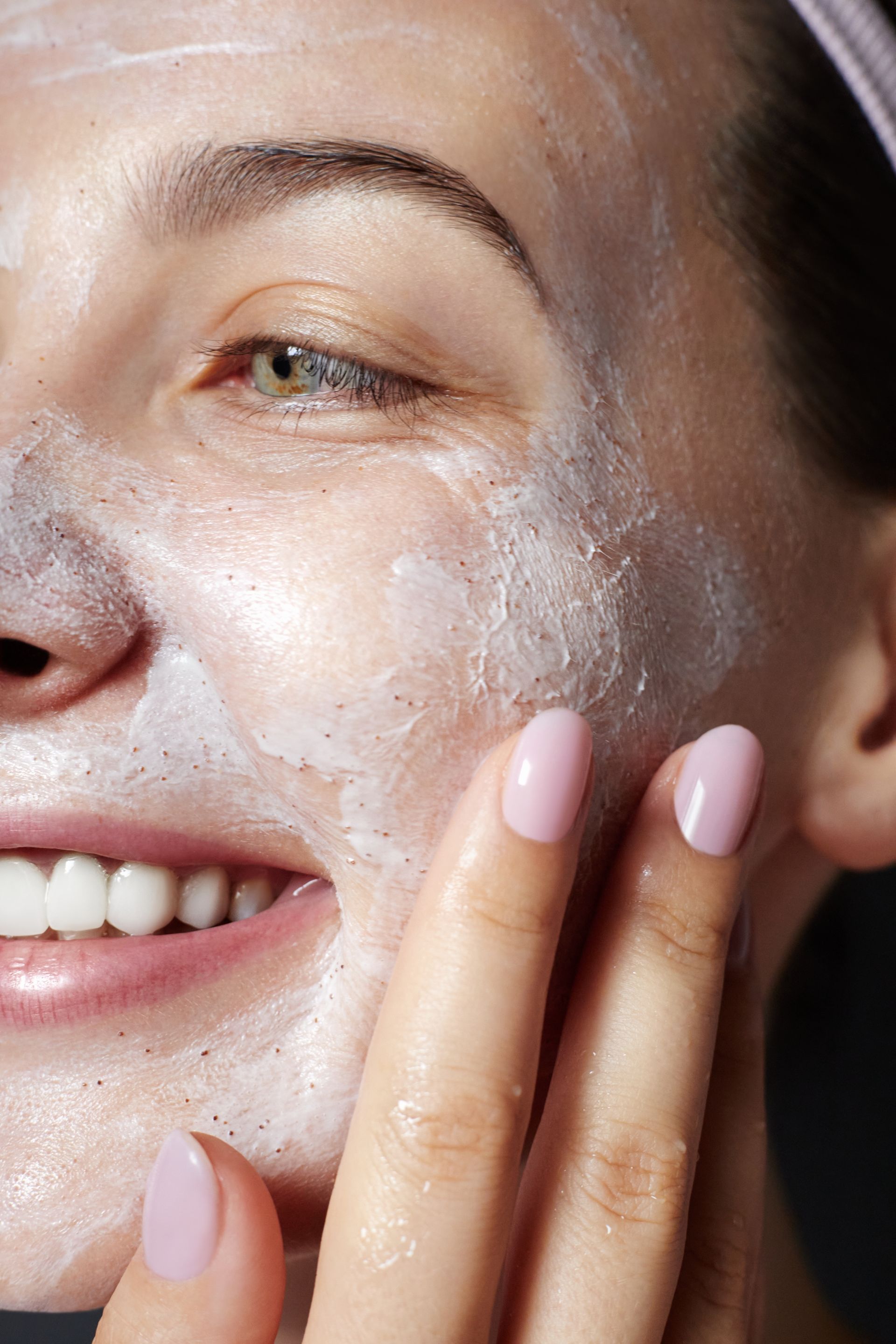 A woman is applying a white mask to her face.