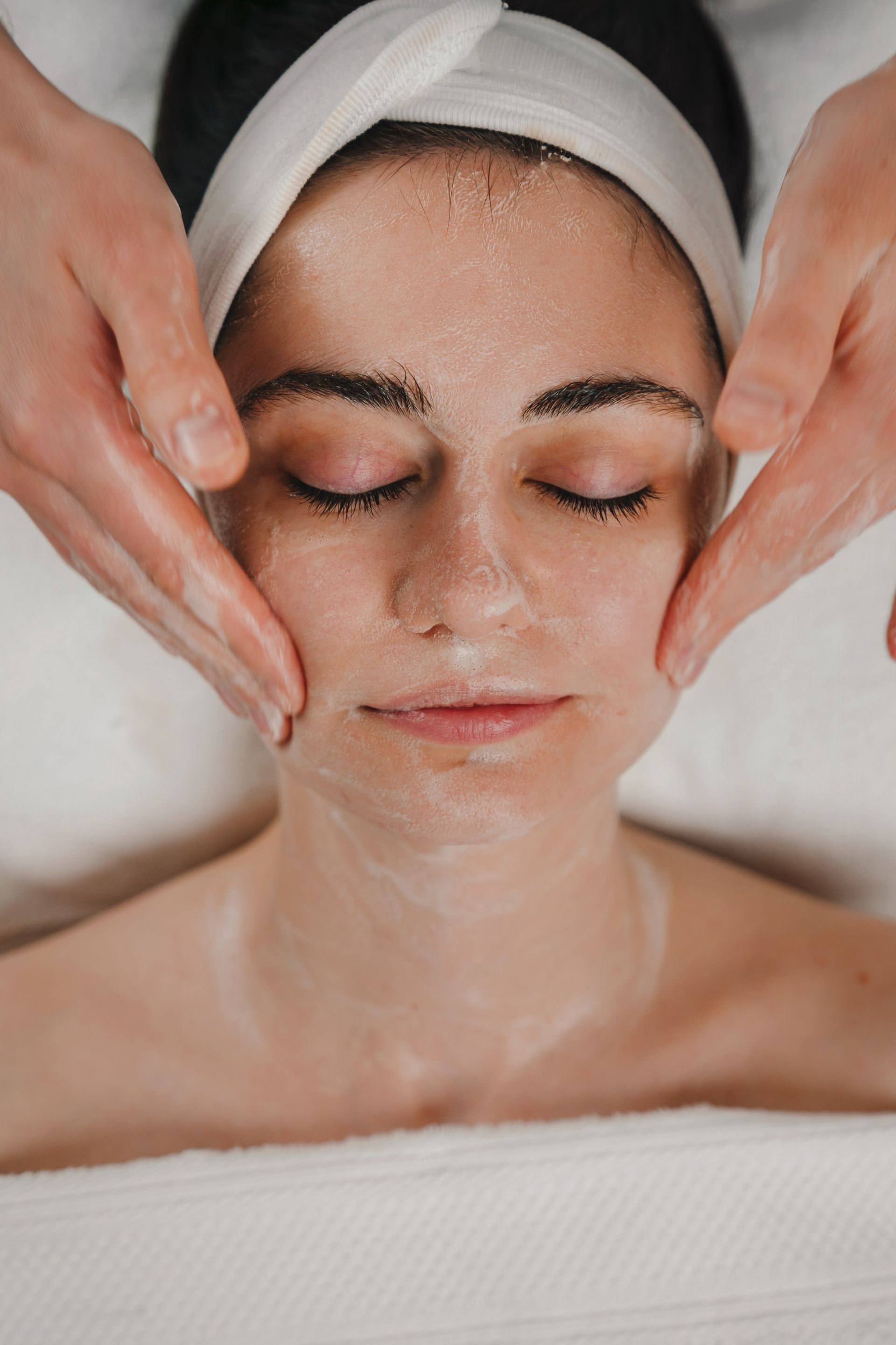 A woman is getting a facial massage at a spa.