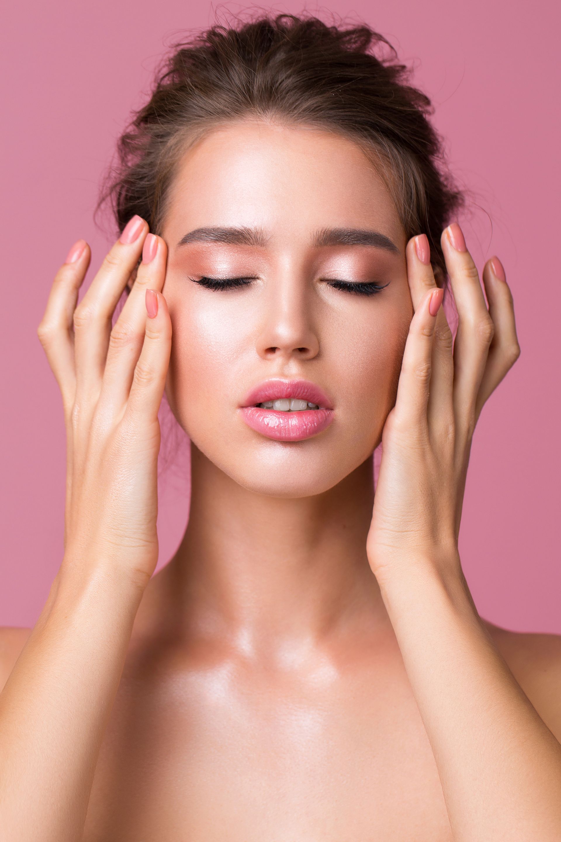 A woman with her eyes closed touching her face