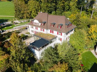 Die alte Villa Kästeli umgeben von Bäumen und Wäldern ist auf dem Bild zu sehen.