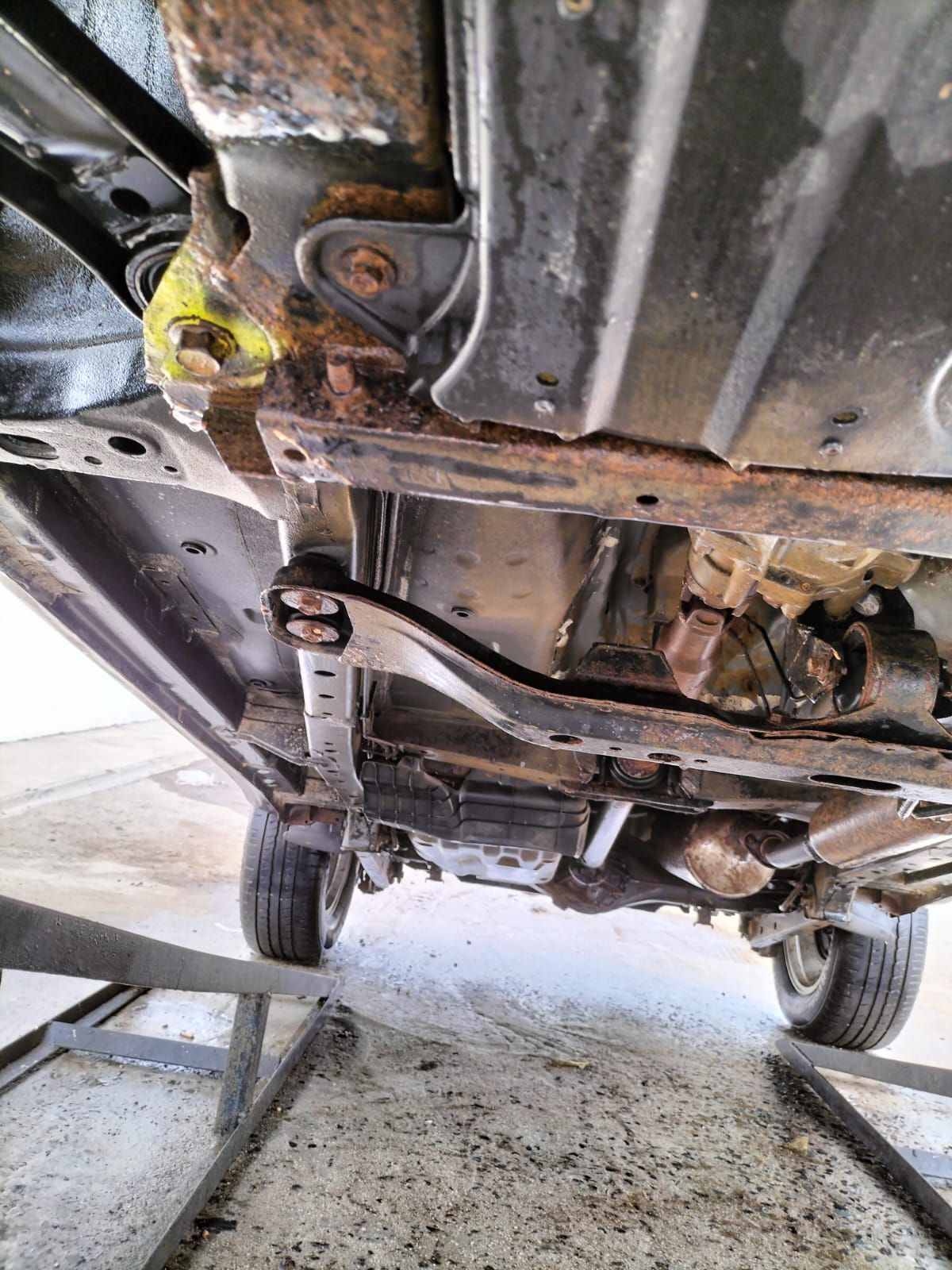 A close up of the underside of a car on a lift. Prevent this by sending your vehicle to Anthony Anti-Corrosion Coatings.