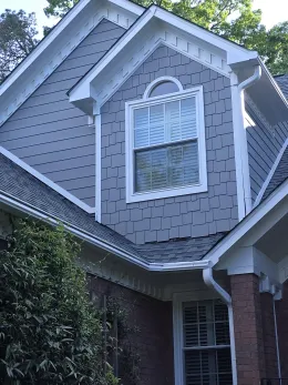 House exterior with grey siding, white trim, and a window.