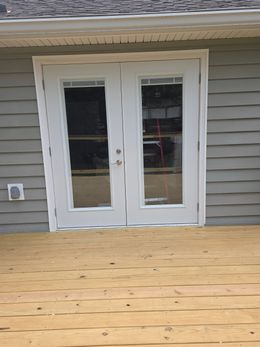 Hand opening a silver door handle on a white door.