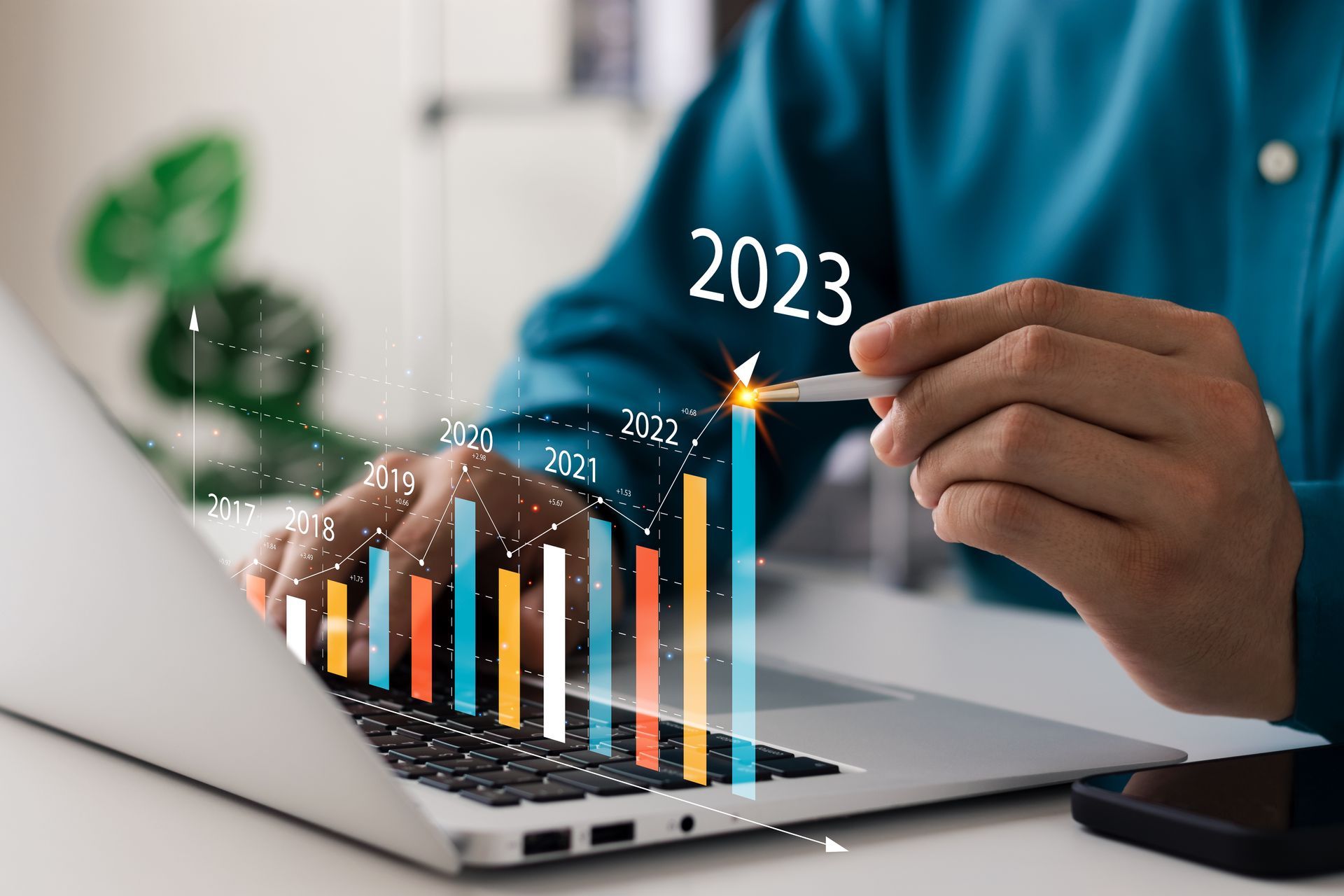 Businessmen at his laptop computer looking at potential profits for 2023 with 3D infographics.