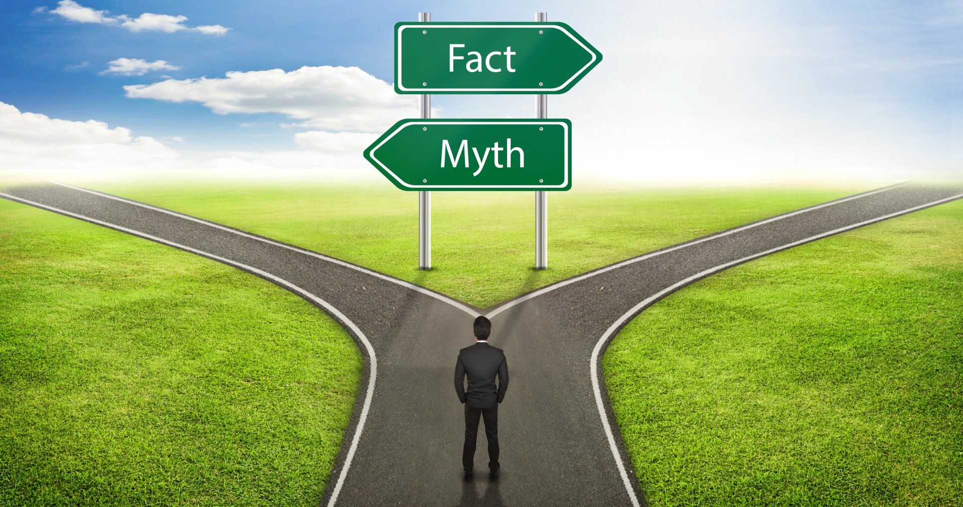 Businessman at a crossroads with the road of facts going one way and the road of myths going another