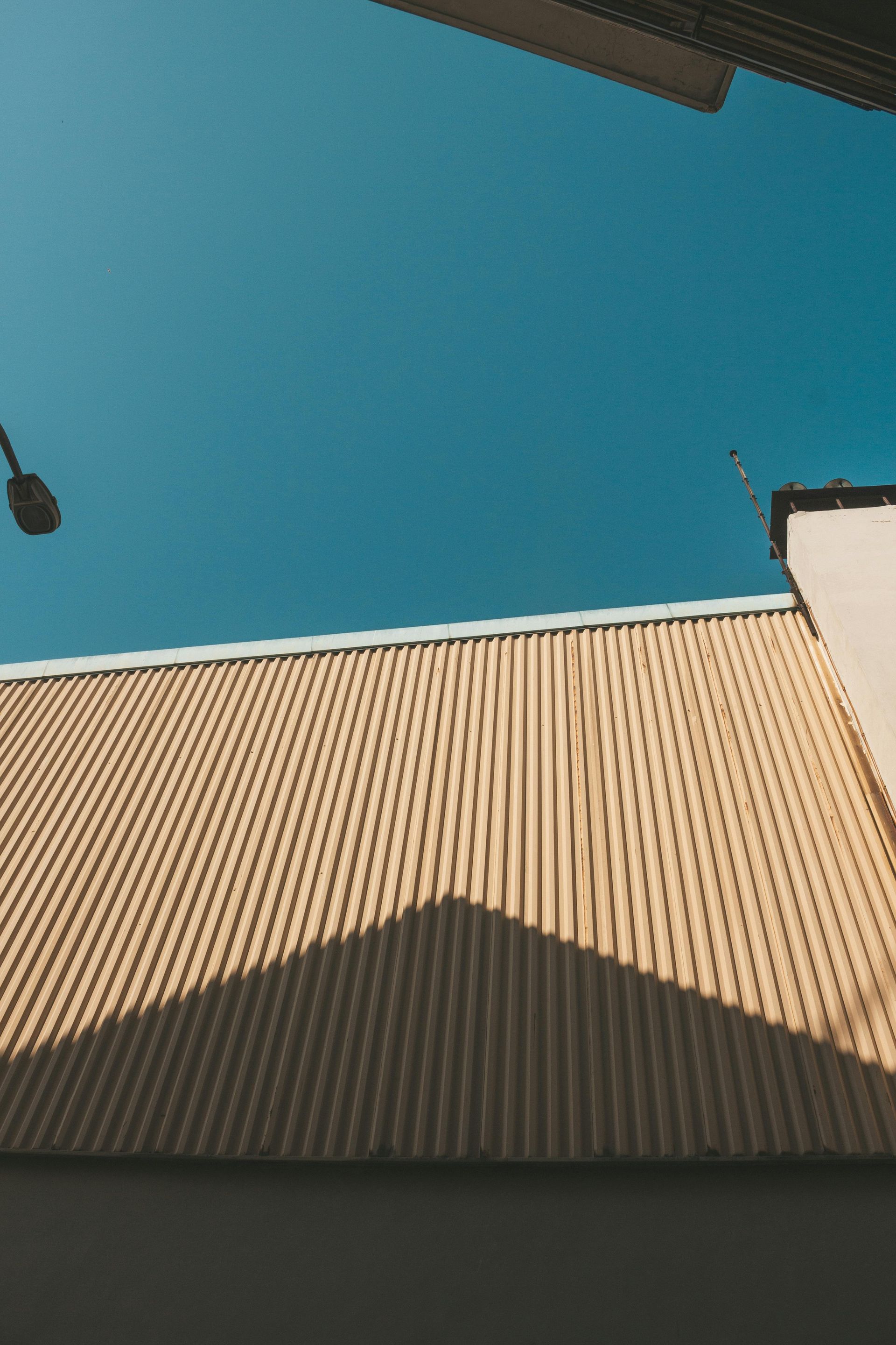 Yellow corrugated building roof against a bright blue sky.