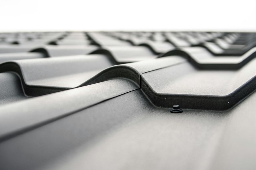 Close-up view of a black metal roof with interlocking panels, angled perspective, daylight.