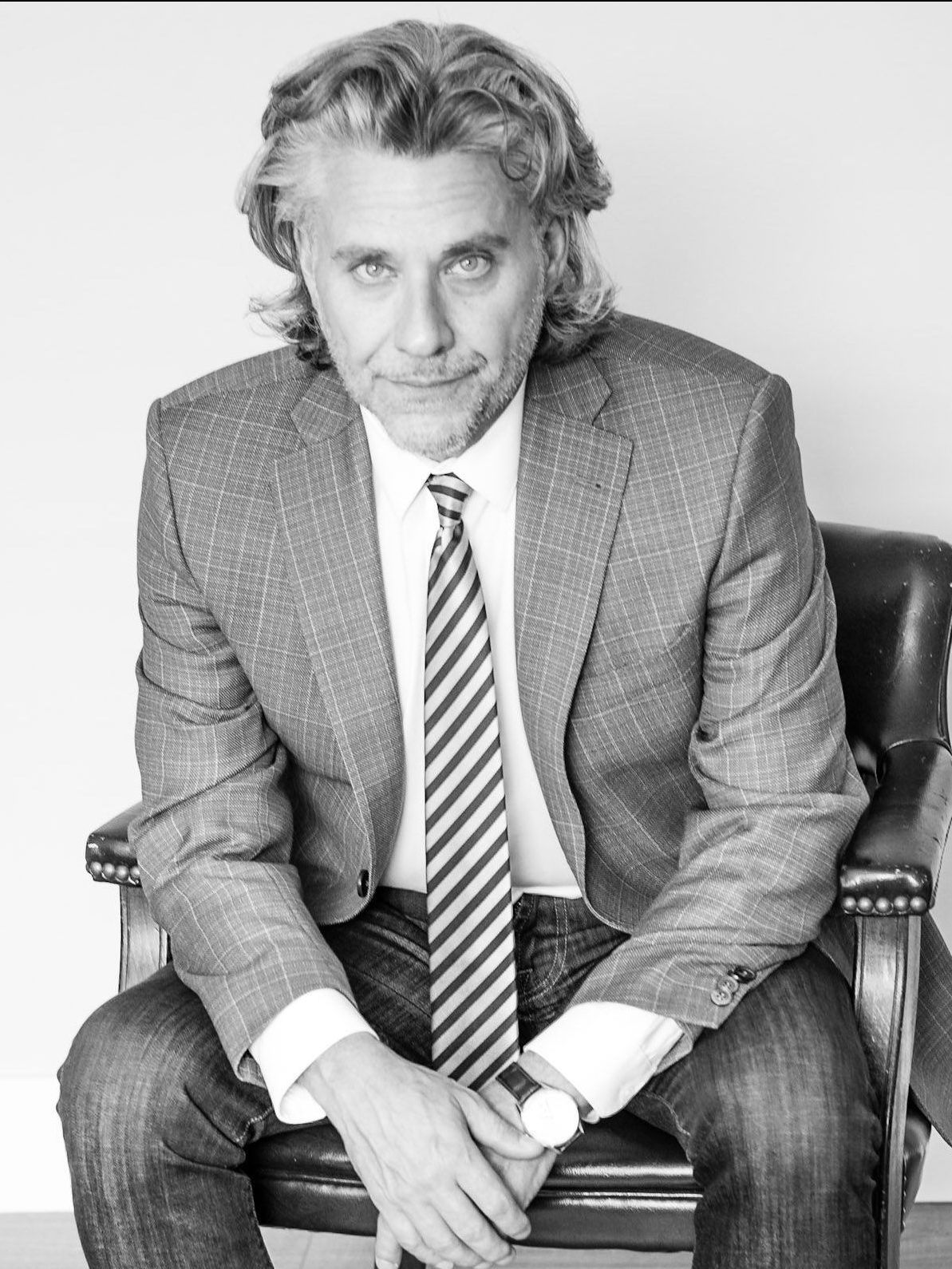 A man in a suit and tie is sitting in a chair