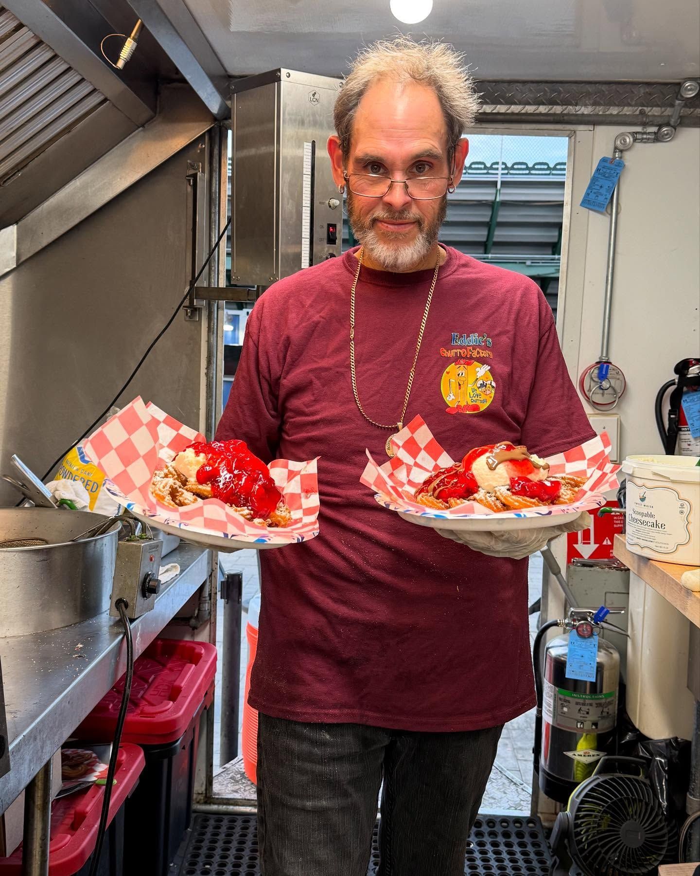 Person in a kitchen holding two trays of red and white checkered baskets filled with food