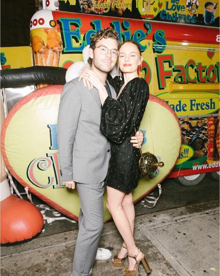 Two people posing in gray outfits in front of a colorful “Big Fat” food truck sign.