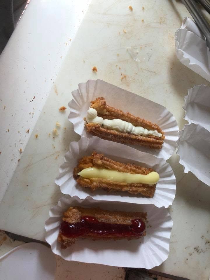Three éclairs in paper cups on a white tray: white, cream, and chocolate toppings.