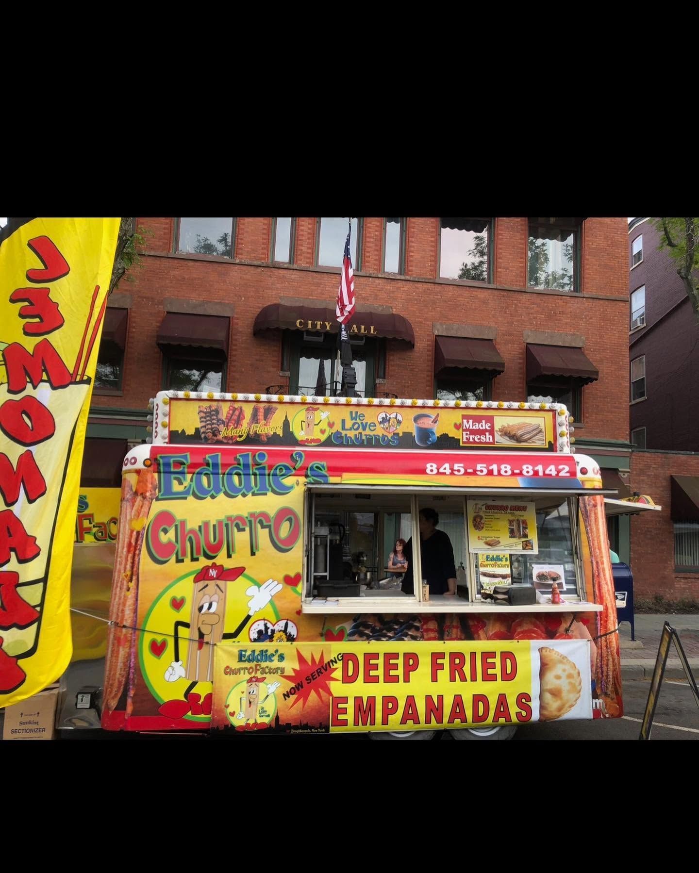 Bright food stand with red-yellow signage advertising deep-fried empanadas on a city street