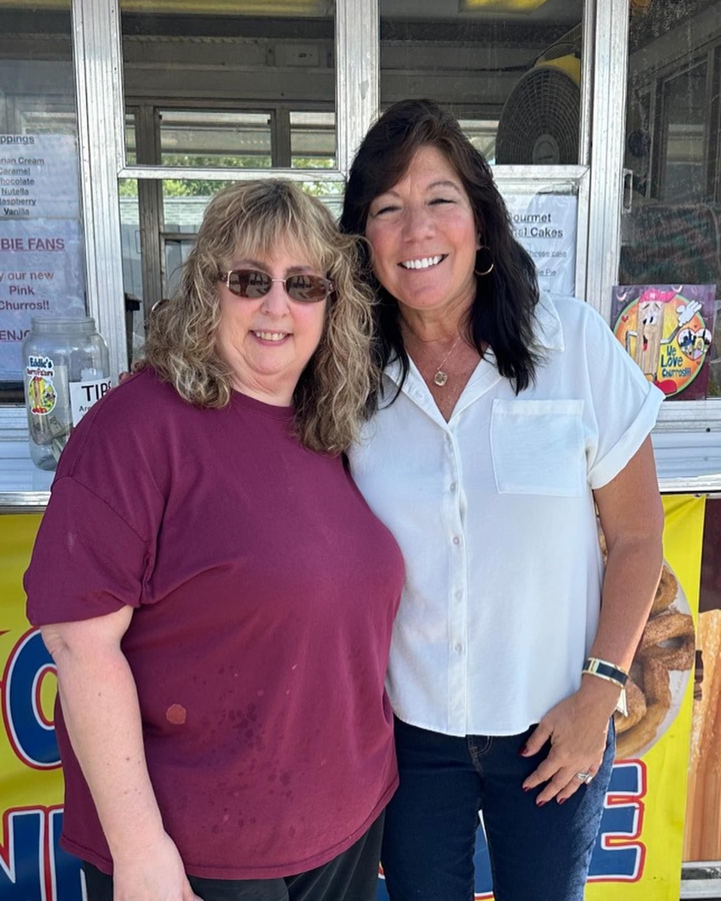 Two smiling people standing together in front of a concession stand window