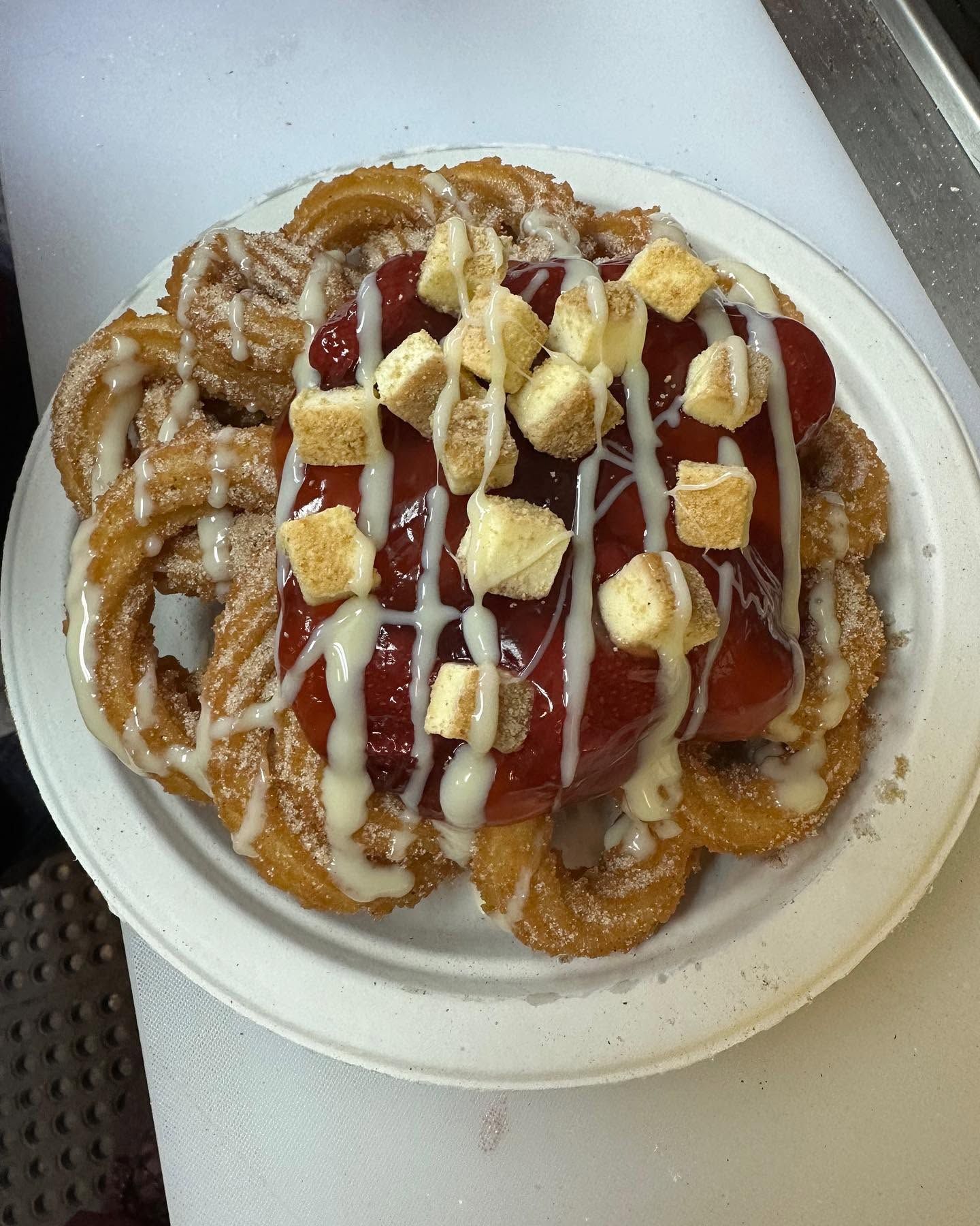 Plate of fried dough pastries topped with strawberries, whipped cream, and powdered sugar on a counter