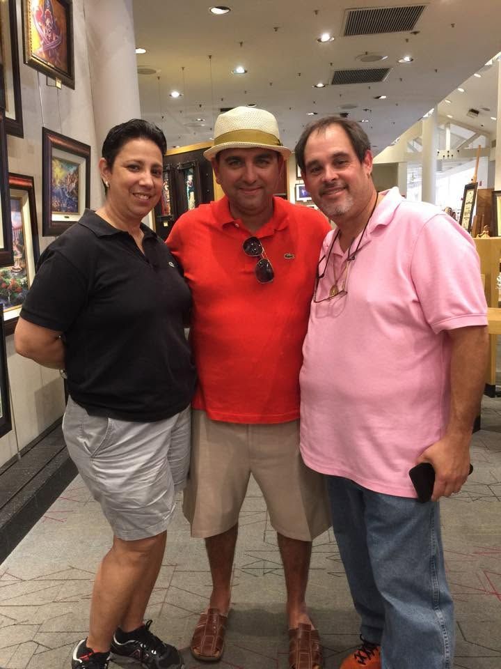 Three people posing indoors, with one in a red shirt and straw hat, flanked by black and pink shirts.