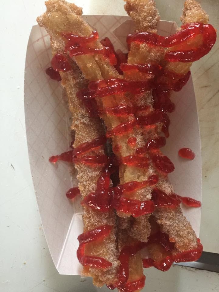 Paper tray of golden fried pastry drizzled with red syrup or sauce