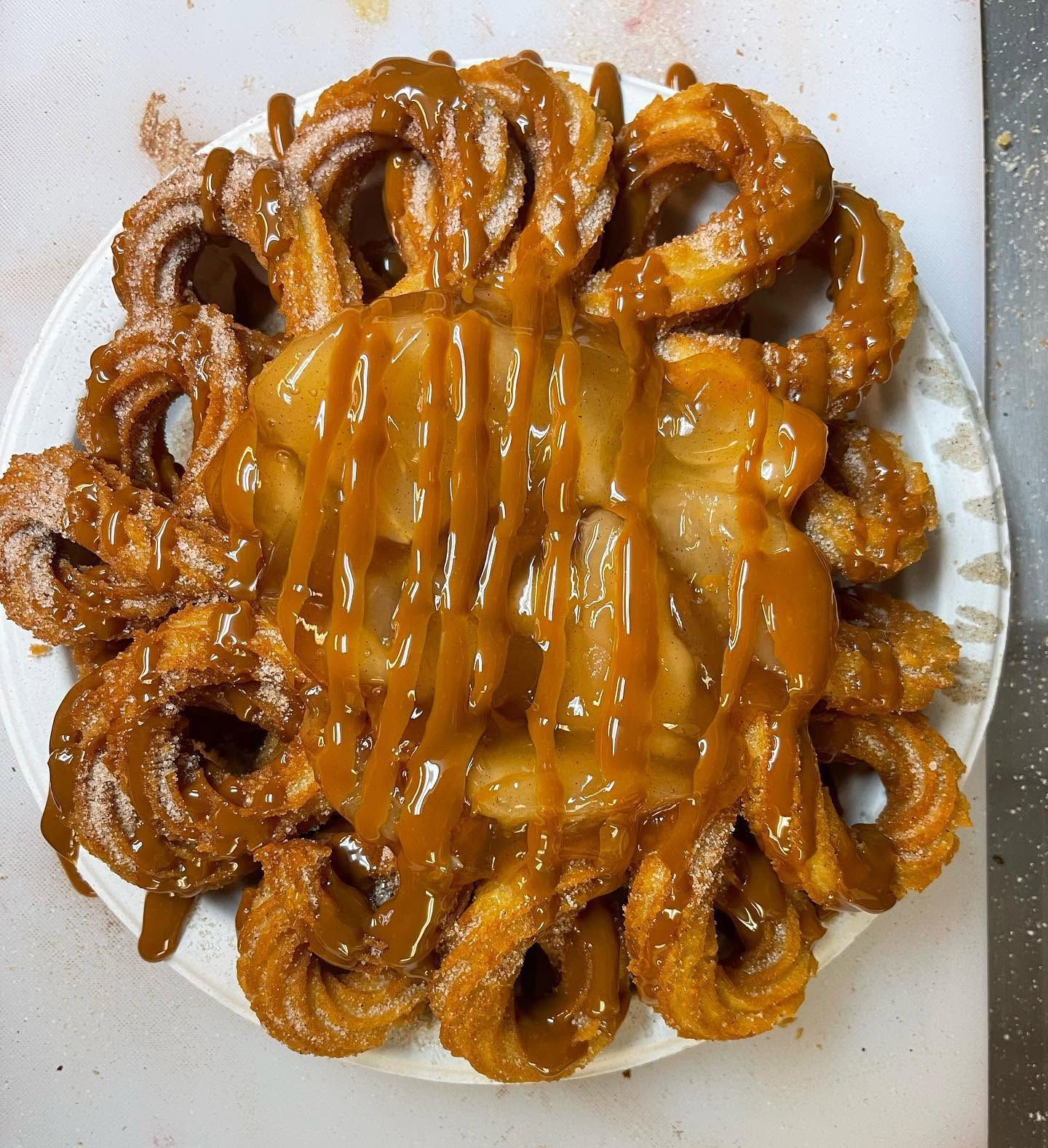 Assorted glazed doughnuts topped with caramel-like drizzle on a white plate