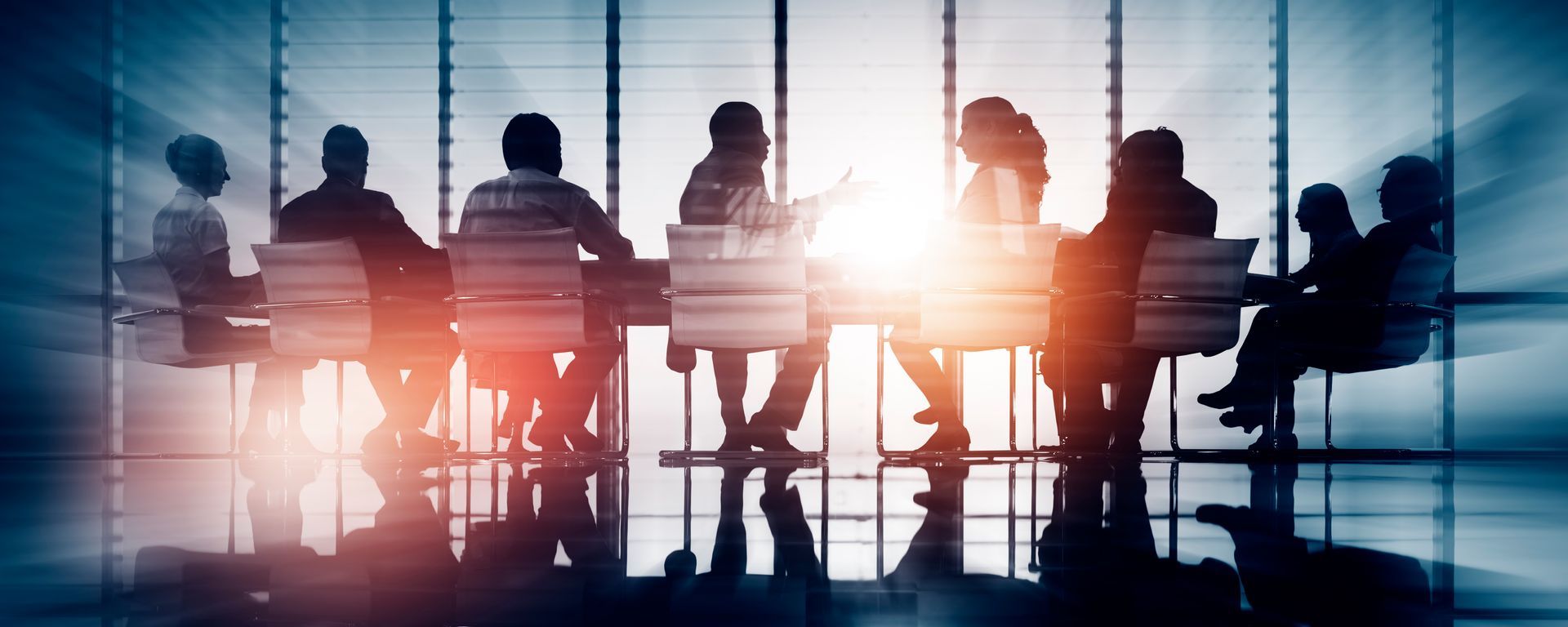 Silhouetted professionals sit around a conference table in a bright, modern office with floor-to-ceiling windows. Silhouetted professionals sit around a conference table in a bright, modern office with floor-to-ceiling windows.