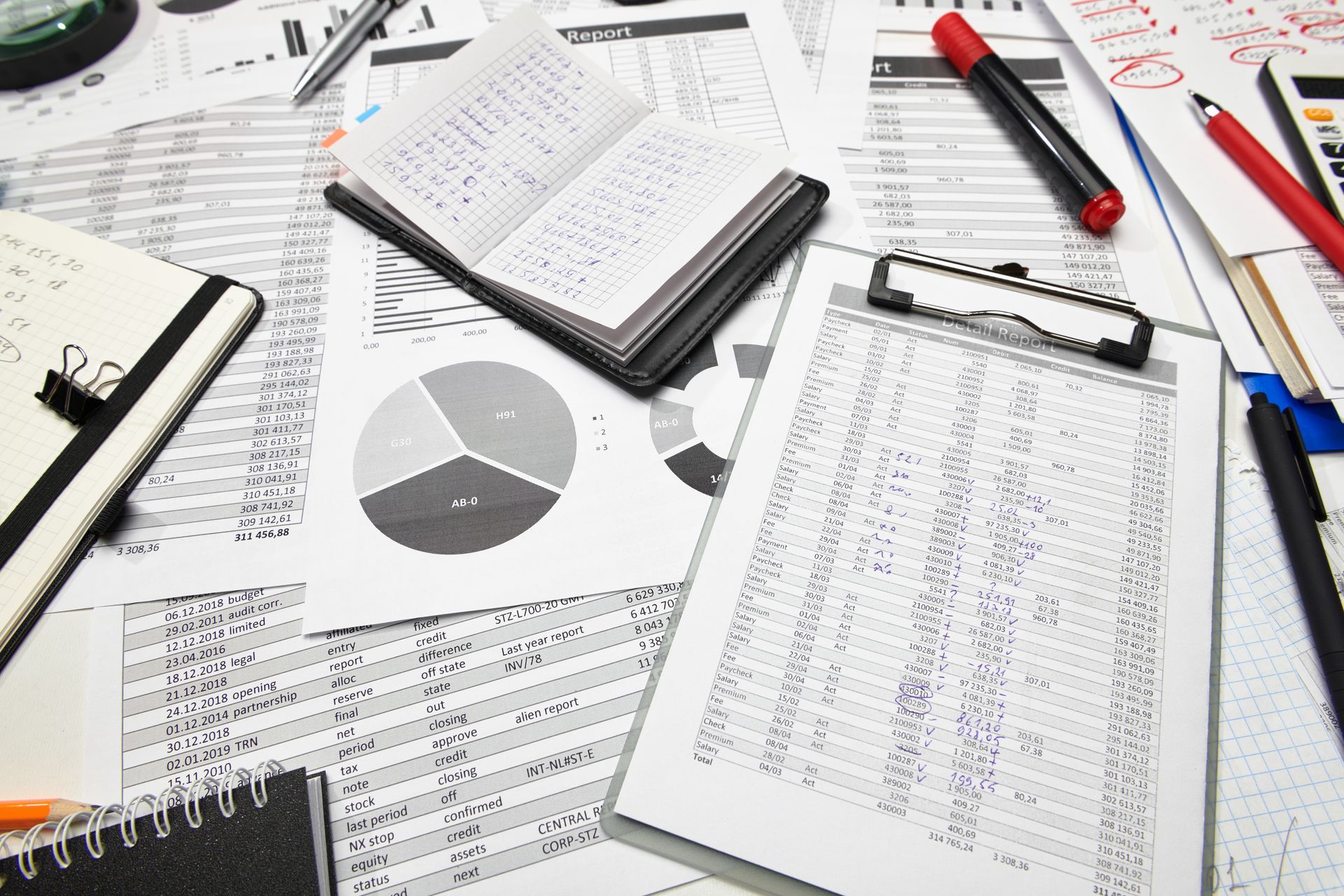 A workspace with financial documents, a pie chart, notebooks, and pens, representing a desk during business analysis. A workspace with financial documents, a pie chart, notebooks, and pens, representing a desk during business analysis.