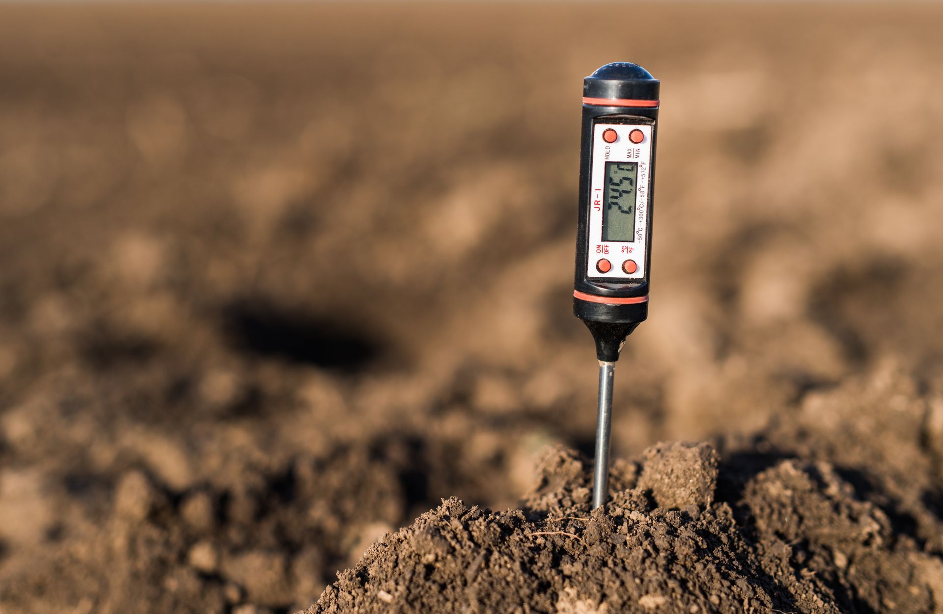 Digital soil moisture meter inserted in dry brown soil in a field