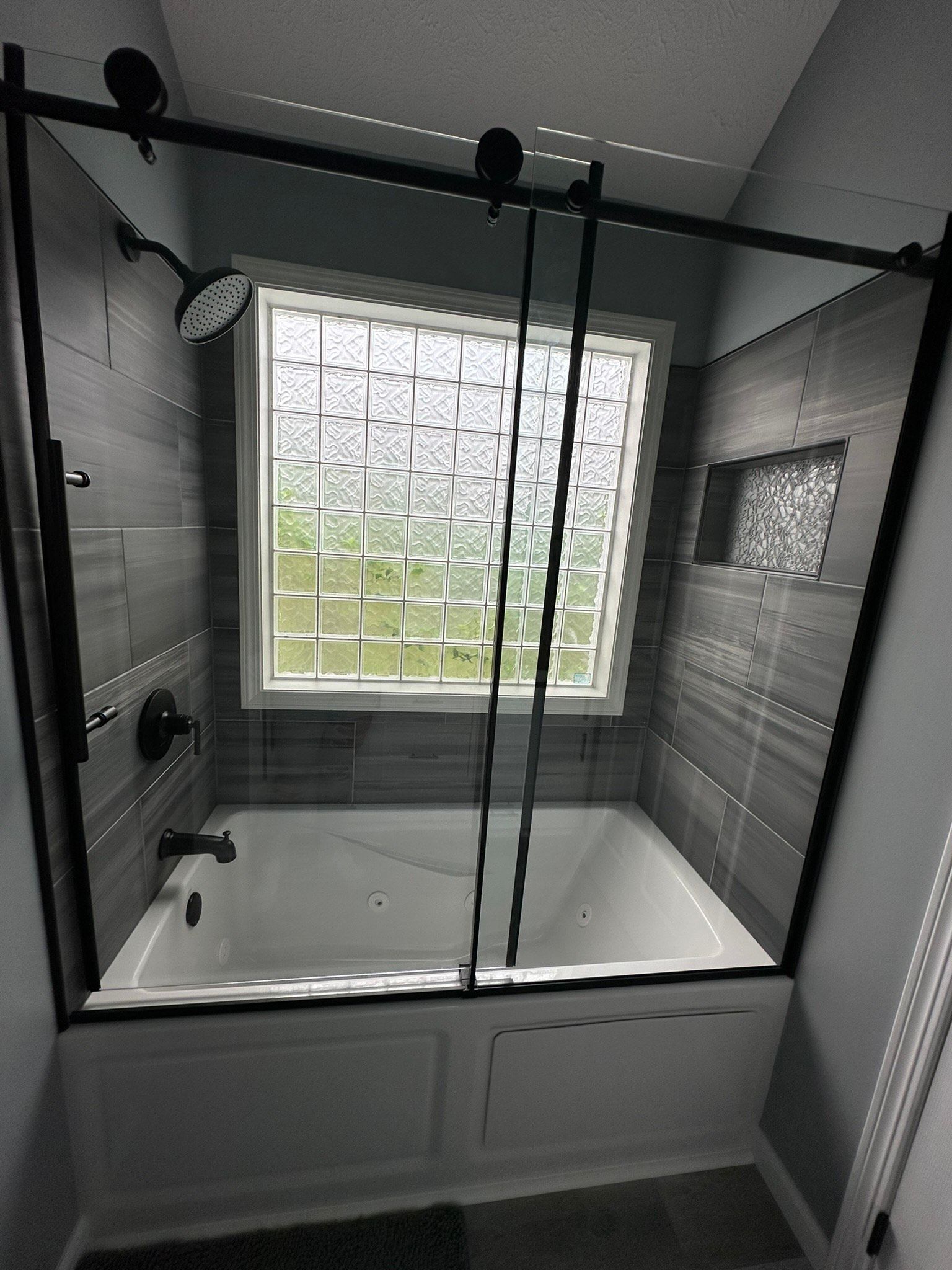 A bathroom with a tub , shower , and window.