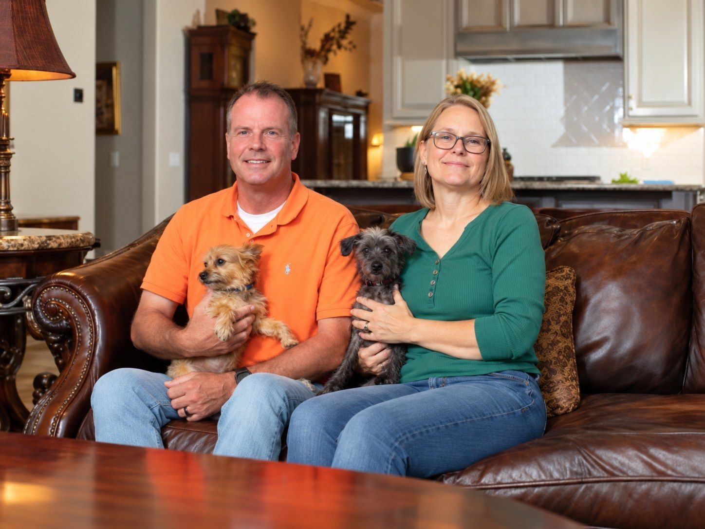 John's Dignity founders Kenneth and his wife at home on their sofa, each holding one of their small dogs