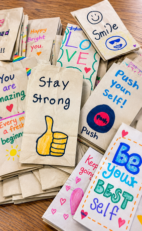 Colorful motivational hand-drawn paper signs with messages like “Stay strong,” “Be yourself,” and “Smile.”